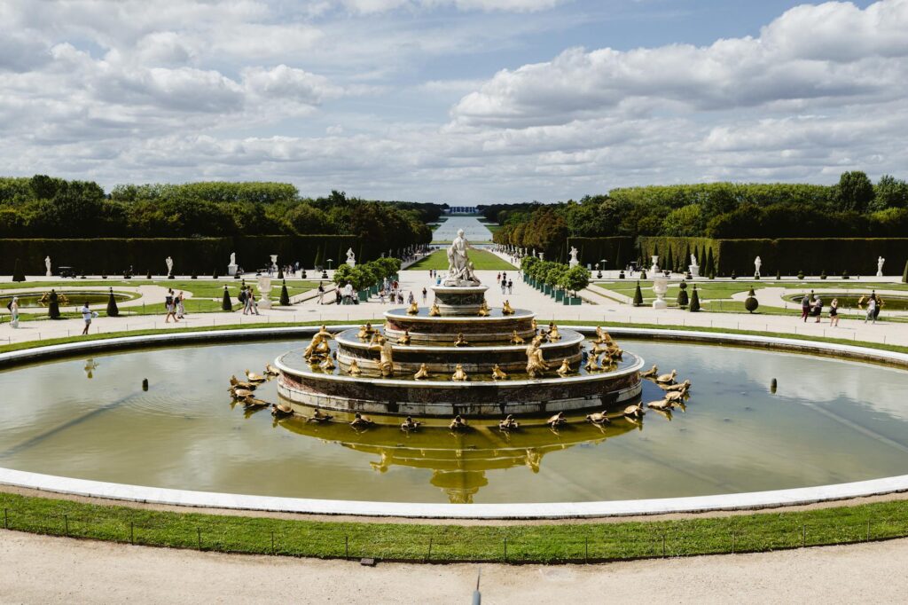 French Aristocracy 2 - Grand Boudoir A stunning view of the Grand Fountain in the Versailles gardens, France, under a blue sky.