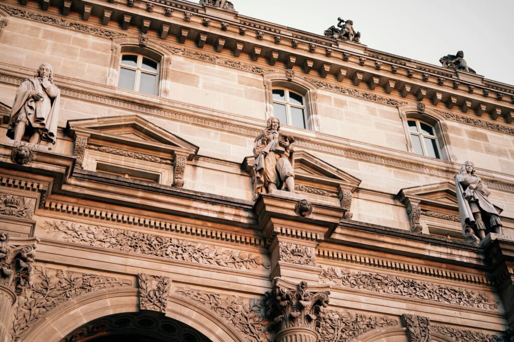 French Aristocracy 3 - Grand Boudoir Facade of the Louvre Museum in Paris featuring intricate sculptures and classic architecture.