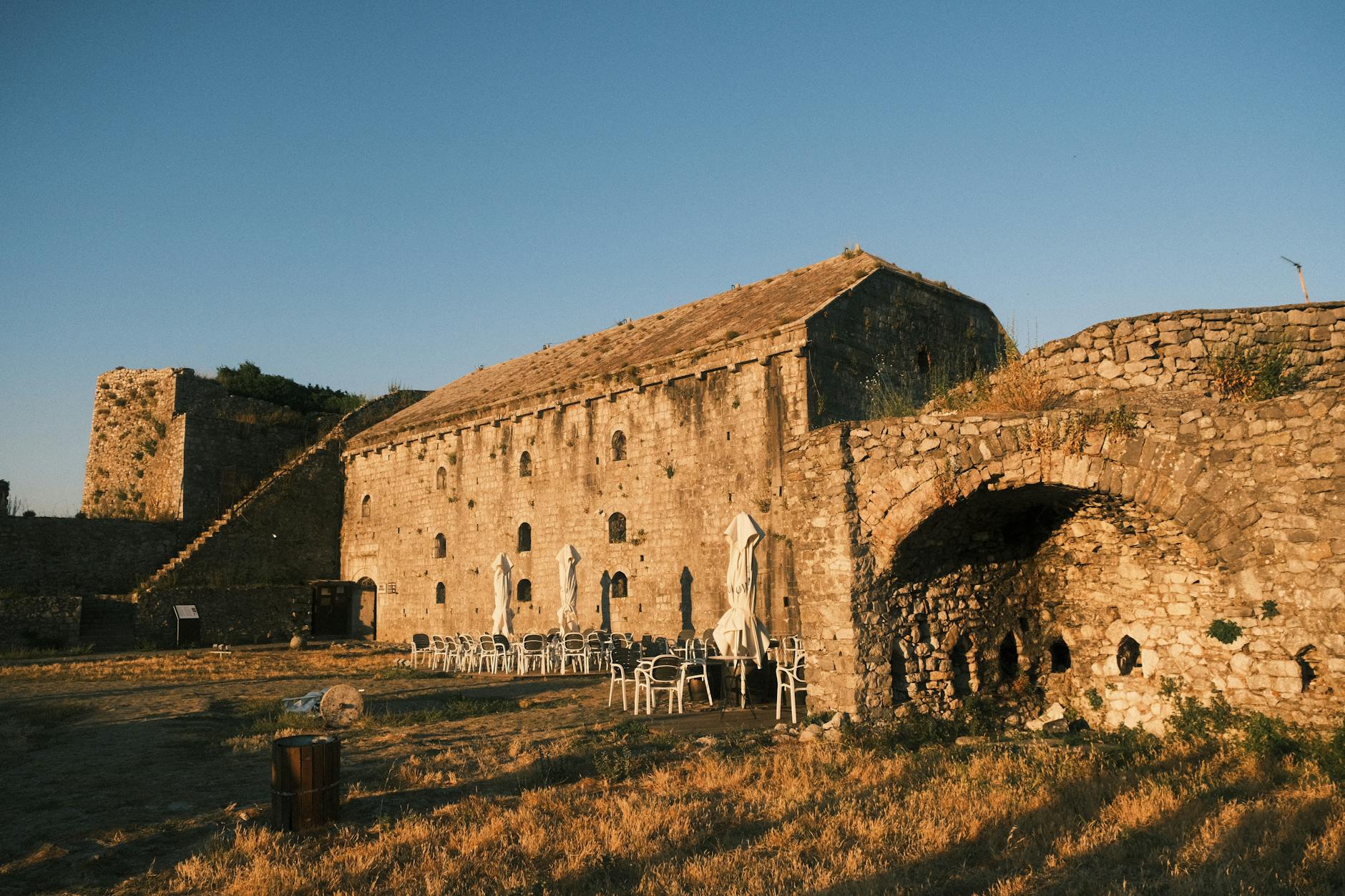 Within Stone and Shadow The Enduring Spell of Castle Interiors 6 - Grand Boudoir Historic Shkodër Castle in Albania at sunset with empty outdoor seating.