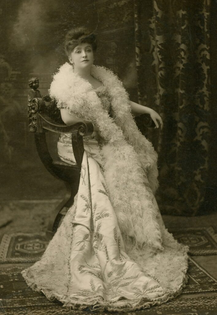 Victorian lingerie 1 - Grand Boudoir A woman in an elaborate gown with a feather boa sitting in a chair