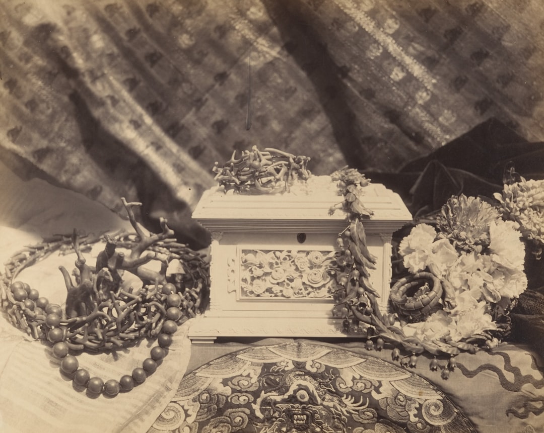 photo 1783686006443 88bdcf8acc00 - Grand Boudoir An ornate white casket surrounded by decorative garlands and jewelry