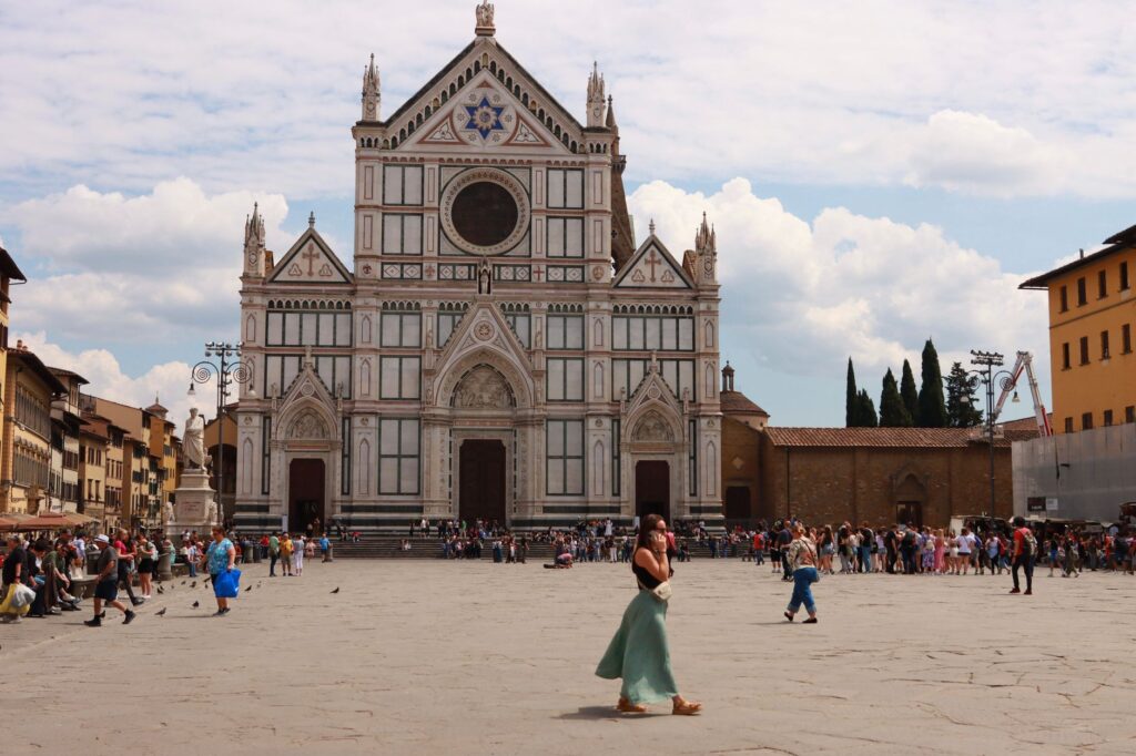 Santa Croce Basilica with visitors in Florence, Italy on a sunny day.